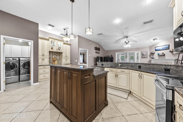 kitchen with separate washer and dryer, sink, dark stone counters, hanging light fixtures, and cream cabinets