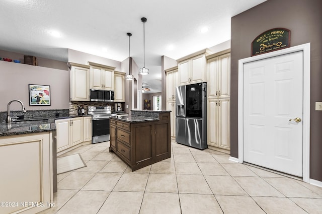 kitchen featuring sink, hanging light fixtures, light tile patterned floors, appliances with stainless steel finishes, and cream cabinets