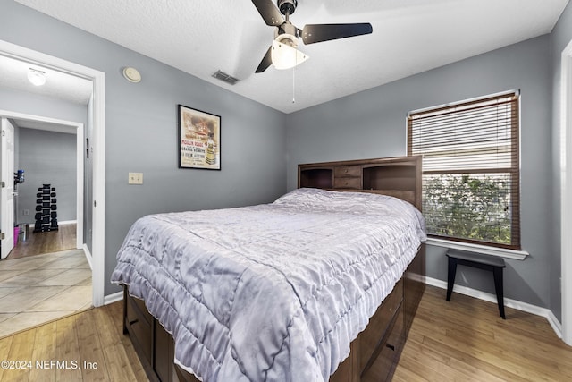 bedroom featuring ceiling fan, a textured ceiling, and light wood-type flooring