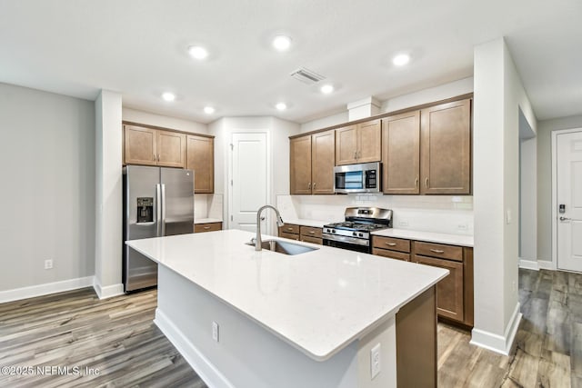 75484 Banyan Way, Yulee, FL 32097 - kitchen featuring stainless steel appliances, a sink, baseboards, light wood-style flooring, and backsplash
