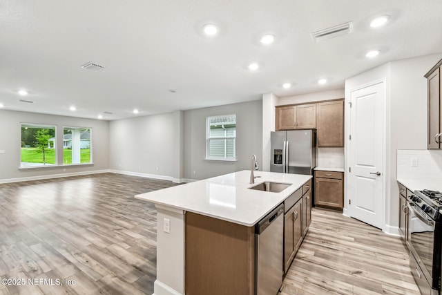 75484 Banyan Way, Yulee, FL 32097 - kitchen with a sink, appliances with stainless steel finishes, light wood-style floors, light countertops, and an island with sink