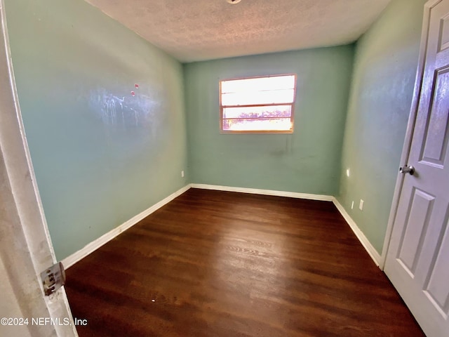 unfurnished room featuring a textured ceiling and dark hardwood / wood-style floors