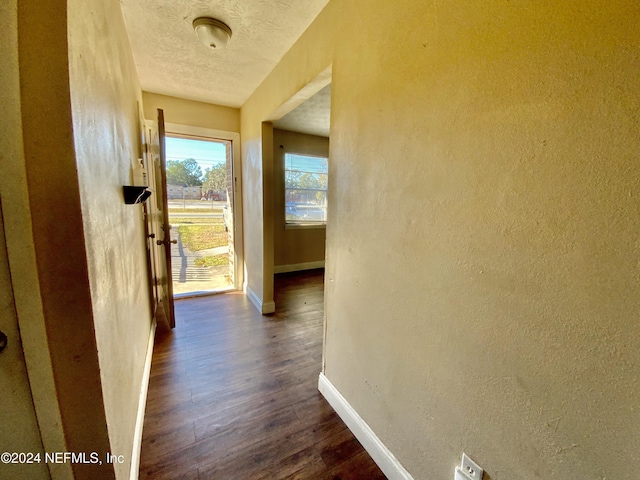 corridor featuring a textured ceiling and dark hardwood / wood-style flooring