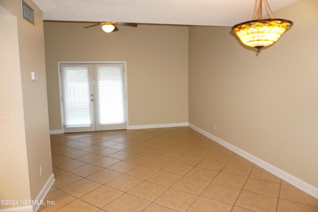 tiled spare room with ceiling fan, lofted ceiling, a textured ceiling, and french doors