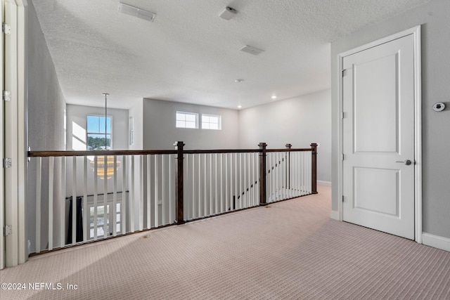 hall featuring light colored carpet and a textured ceiling