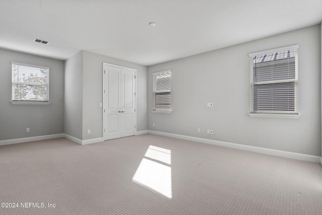 unfurnished bedroom with light carpet and a closet