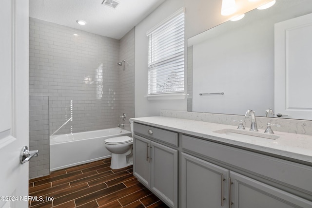 full bathroom with vanity, tiled shower / bath combo, and toilet