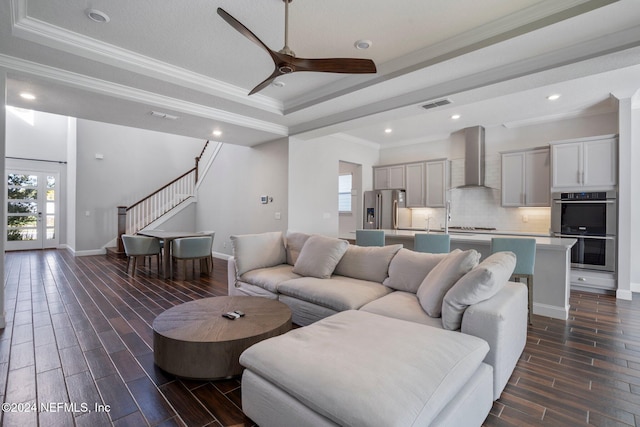 living room with dark hardwood / wood-style floors, a tray ceiling, ornamental molding, and ceiling fan