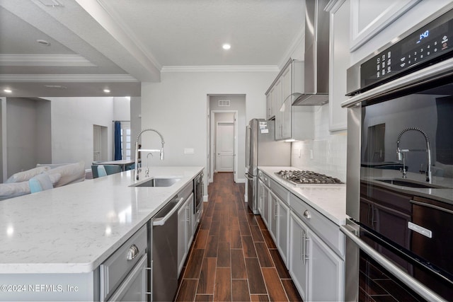 kitchen with a kitchen island with sink, dark wood-type flooring, sink, wall chimney exhaust hood, and stainless steel appliances