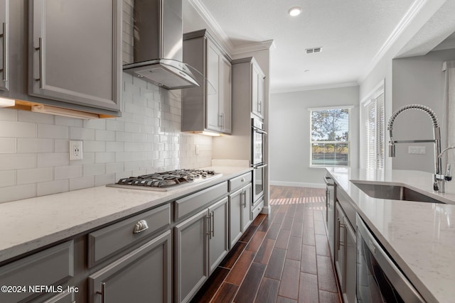 kitchen featuring gray cabinets, wall chimney range hood, sink, and ornamental molding