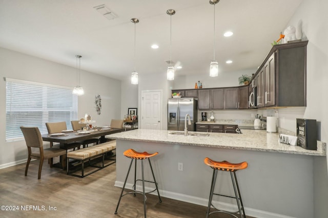 kitchen featuring hanging light fixtures, kitchen peninsula, dark wood-type flooring, and appliances with stainless steel finishes