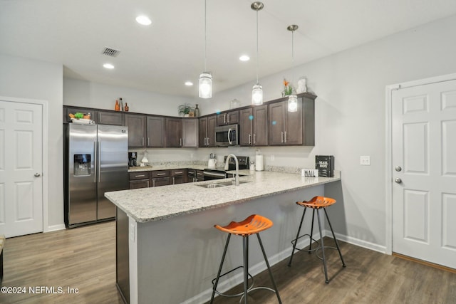 kitchen featuring pendant lighting, dark brown cabinetry, sink, and appliances with stainless steel finishes