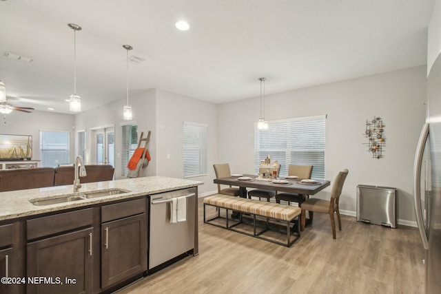 kitchen with decorative light fixtures, sink, appliances with stainless steel finishes, and light hardwood / wood-style flooring