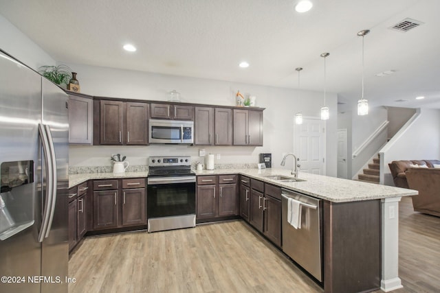 kitchen with sink, hanging light fixtures, light hardwood / wood-style floors, kitchen peninsula, and stainless steel appliances