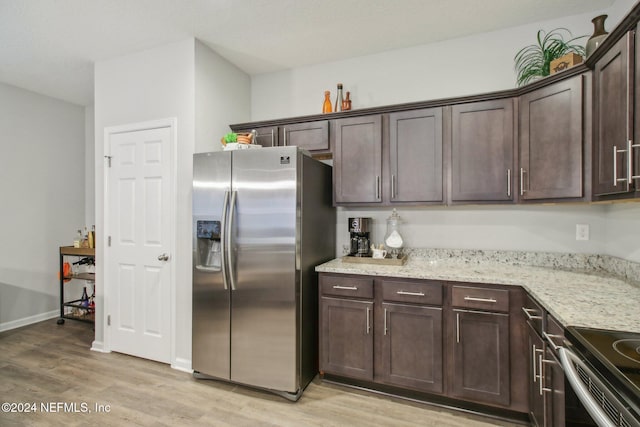 kitchen featuring light stone countertops, appliances with stainless steel finishes, light wood-type flooring, and dark brown cabinets