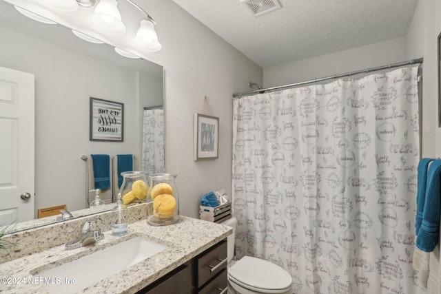 bathroom with curtained shower, vanity, a textured ceiling, and toilet