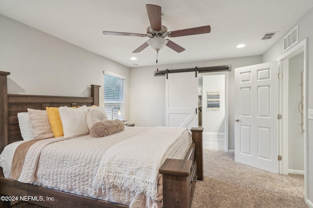 carpeted bedroom with a barn door and ceiling fan