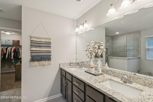 bathroom with tile patterned flooring, vanity, a textured ceiling, and walk in shower