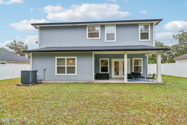 rear view of house with a patio, cooling unit, and a lawn