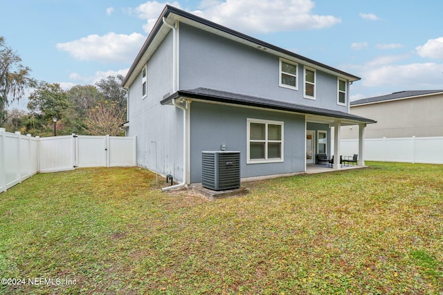 back of property with a patio area, a yard, and central AC