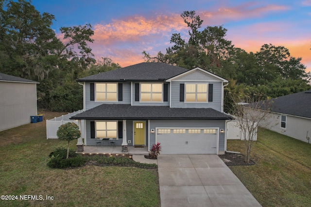 view of front of property featuring a porch, a garage, and a yard