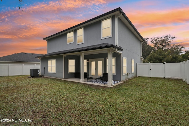 back house at dusk with a yard, a patio, and cooling unit