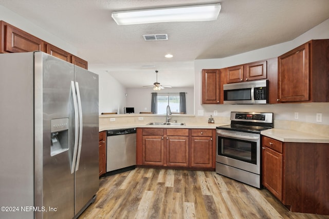 kitchen featuring sink, stainless steel appliances, light hardwood / wood-style floors, a textured ceiling, and vaulted ceiling