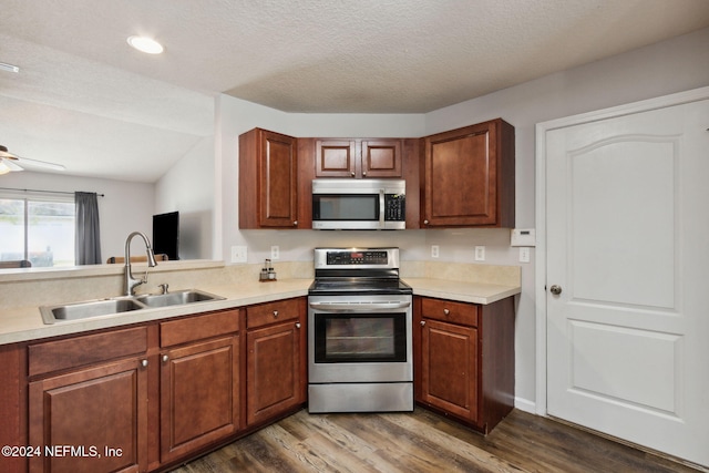 kitchen with sink, stainless steel appliances, dark hardwood / wood-style floors, a textured ceiling, and vaulted ceiling