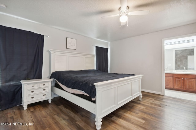 bedroom featuring ceiling fan, sink, dark wood-type flooring, and ensuite bath