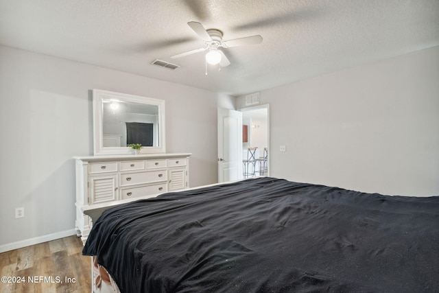 bedroom with a textured ceiling, light hardwood / wood-style flooring, and ceiling fan