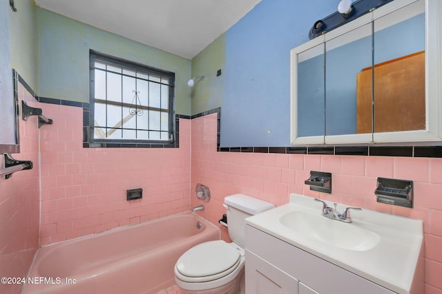 full bathroom with tiled shower / bath combo, toilet, tile walls, and vanity