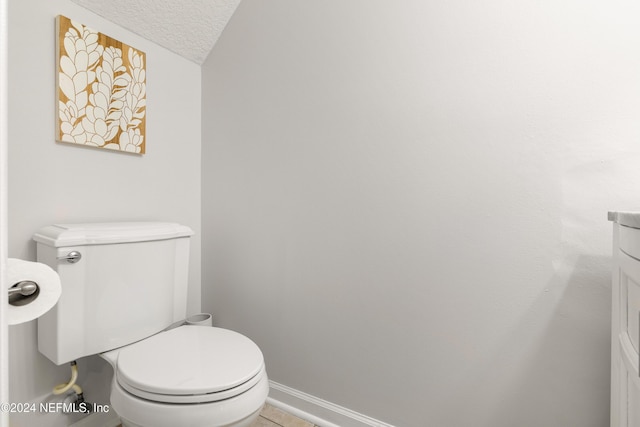 bathroom featuring baseboards, toilet, a textured ceiling, and lofted ceiling