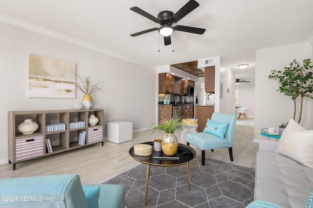 living room featuring a textured ceiling, crown molding, a ceiling fan, and wood finished floors