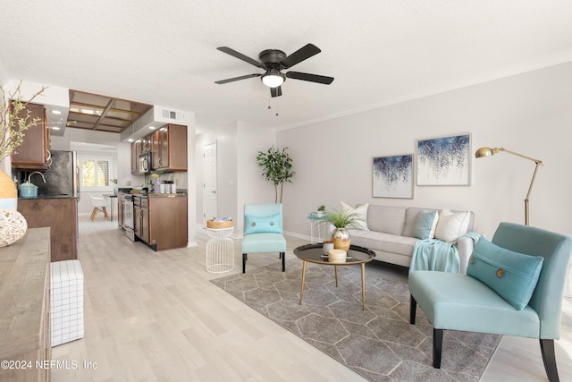 living room featuring visible vents, a textured ceiling, light wood-style floors, baseboards, and ceiling fan