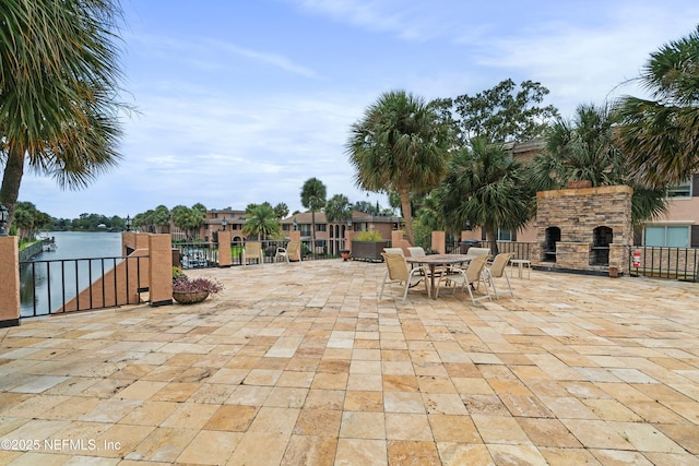 view of patio with an outdoor stone fireplace and fence