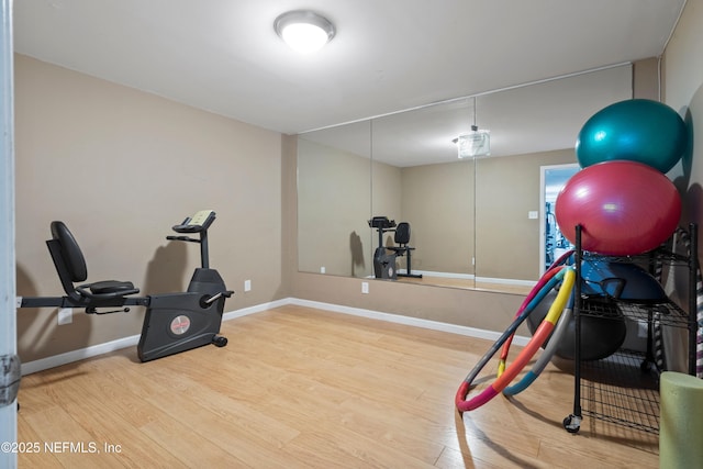 exercise room with baseboards and wood finished floors