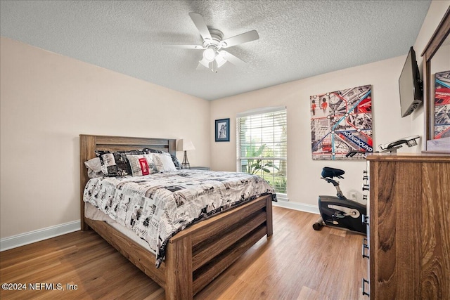 bedroom featuring a textured ceiling, ceiling fan, wood finished floors, and baseboards