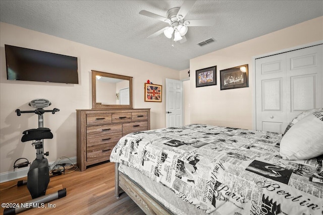 bedroom featuring ceiling fan, wood-type flooring, a textured ceiling, and a closet