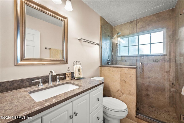 full bathroom featuring a textured ceiling, a stall shower, vanity, and toilet