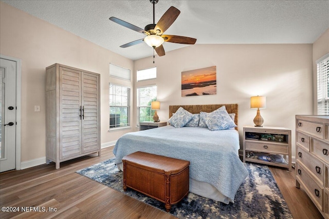 bedroom with vaulted ceiling, ceiling fan, a textured ceiling, wood finished floors, and baseboards