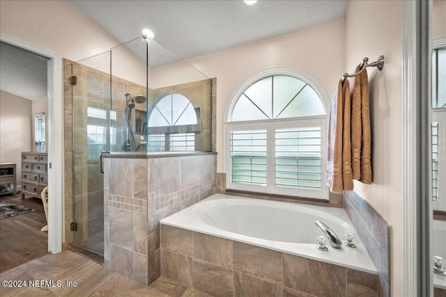 bathroom with plus walk in shower, a textured ceiling, and hardwood / wood-style flooring