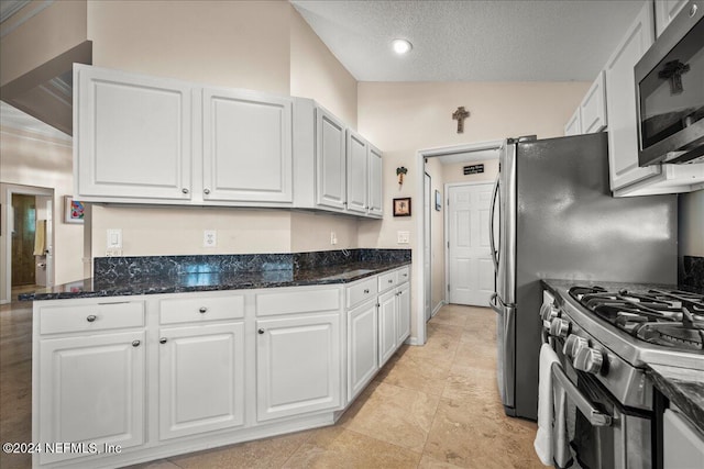 kitchen with stainless steel appliances, dark stone counters, white cabinetry, and vaulted ceiling