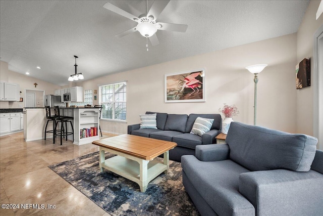 living area with vaulted ceiling, a textured ceiling, and ceiling fan