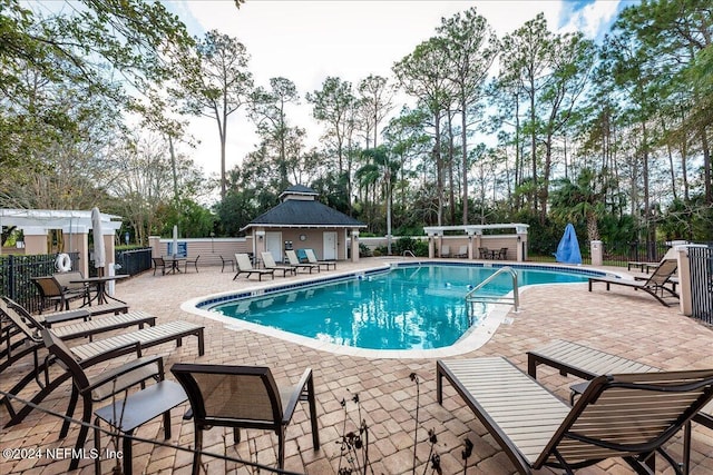 community pool with an outbuilding, a patio, and fence