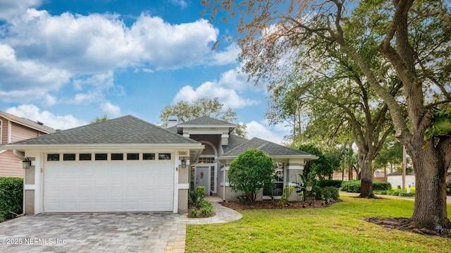 view of front of home featuring a garage, a shingled roof, decorative driveway, and a front yard