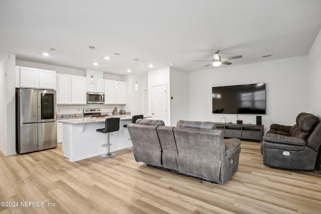 living room featuring ceiling fan and light wood-type flooring