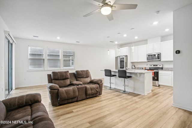 living room with ceiling fan and light wood-type flooring