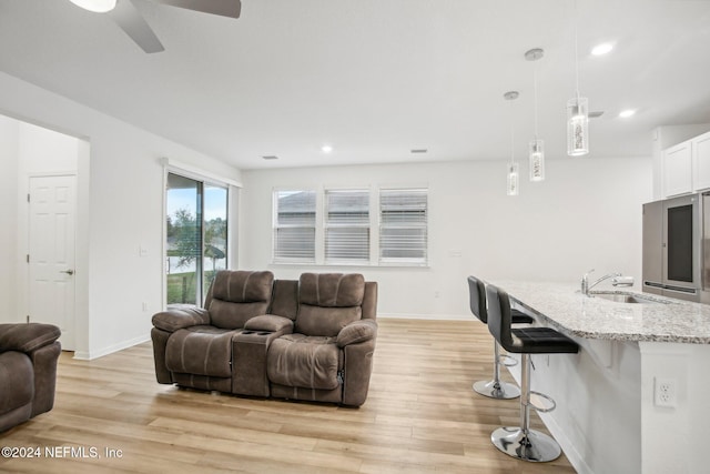 living room featuring light hardwood / wood-style floors, ceiling fan, and sink