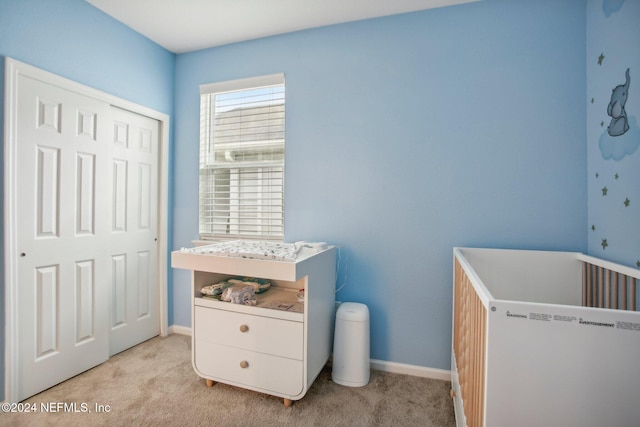 bedroom with a closet, light colored carpet, and a nursery area