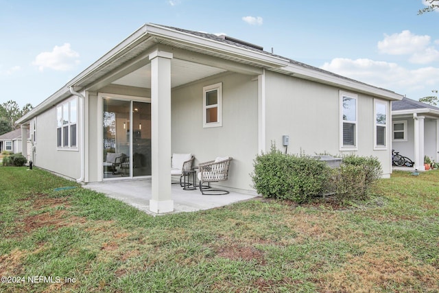 back of property with a lawn and a patio